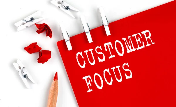 CUSTOMER FOCUS text on red paper with office tools on the white background