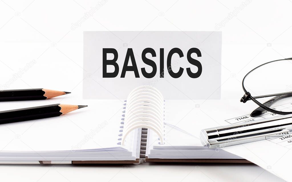 Text BASICS on paper card,pen, pencils,glasses,financial documentation on the table - business concept