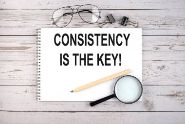 Metinli defter ahşap masadaki kalem, büyüteç ve gözlüklü anahtardır.