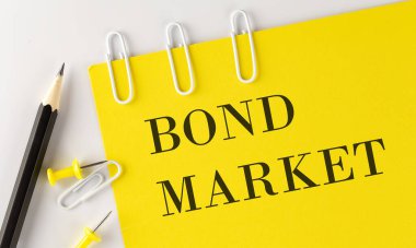 Beyaz arka planda ofis araçları ile sarı kağıt üzerinde BOND MARKET kelime