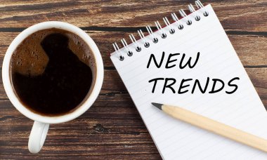 YENİ TRENDS Not Defteri üzerinde metin Tahta arka planda kahve