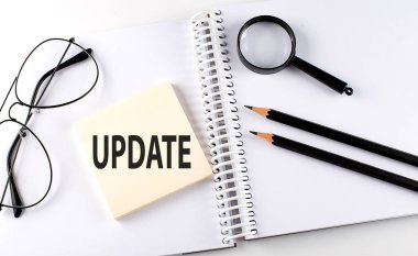 Not defterine kalem, büyüteç ve gözlük takılmış kelime UPDATE üzerine hasta.