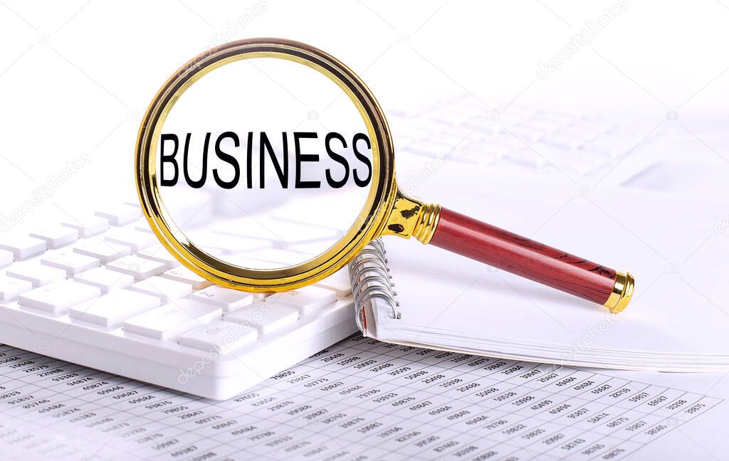 BUSINESS word through magnifying glass on the keyboard on the chart