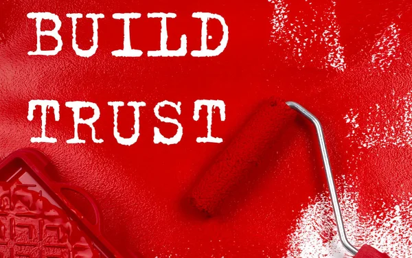 Roller brush with red paint with text BUILD TRUST , business