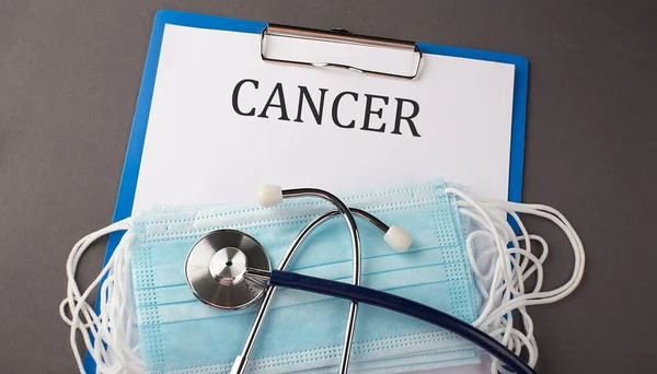 带有纸质文本的文件夹Cancer 放在桌子上 带有听诊器和医疗面罩 — 图库照片