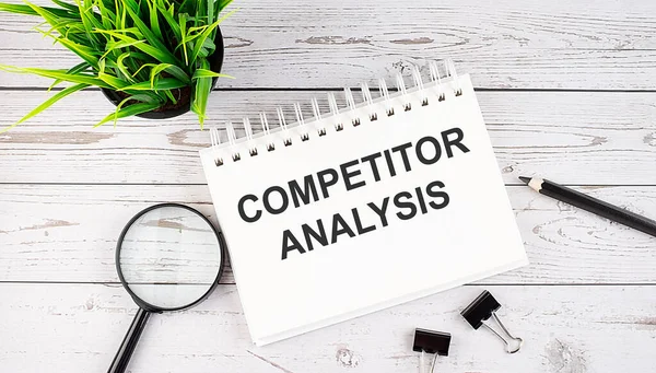 COMPETITOR ANALYSIS text concept write on notebook with office tools on the wooden background