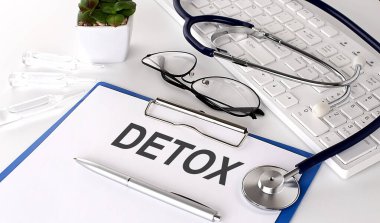 Beyaz arkaplan üzerine DETOX metni. steteskop, gözlük ve klavye