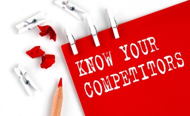 KNOW YOUR COMPETITORS text on the red paper with office tools on the white background