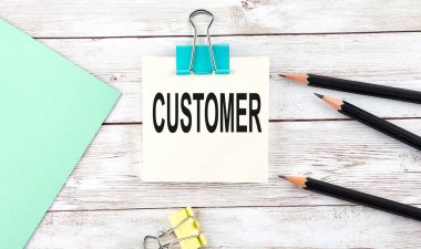 Kalemli çıkartmalar ve tahta arka planda CUSTOMER yazılı defter.