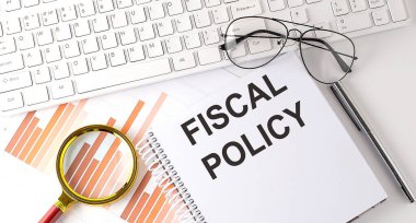 Not defterine klavye, grafik ve gözlük ile yazılmış FISCAL POLICY metni