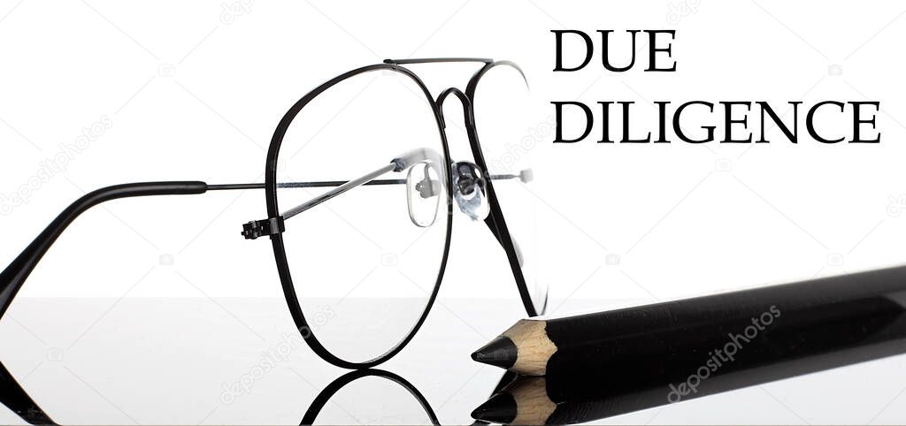 DUE DILIGENCE text. Glasses and pencil isolated on white background