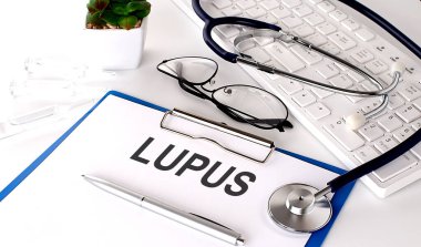 LUPUS beyaz arka planda beyaz kağıt üzerine metin. steteskop, gözlük ve klavye