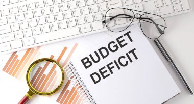 Klavye, çizelge ve gözlük ile deftere yazılmış bütçe metni