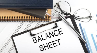 Beyaz arkaplan üzerinde not defterleri, malzemeler, analiz grafiği ile ofis masasının üzerinde Balans SHEET metin.