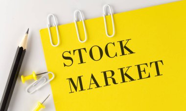 Beyaz arka planda ofis araçları ile sarı kağıt üzerinde STOCK MARKET kelime