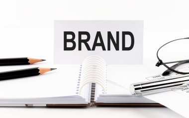 Kağıt kart, kalem, kalem, gözlük, masadaki mali belgeler üzerine Brand metni.