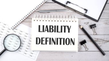 Masaüstünde kalem, ofis araçları ve grafikler ile LIABILITY DEFINITION metin ile not.