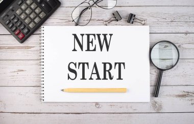 Hesap makinesi ve ofis araçları ile beyaz arkaplan üzerinde NEW Başlat metni ile boş defter.