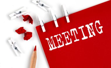 Beyaz arkaplanda ofis araçlarıyla kırmızı kağıt üzerinde toplantı metni