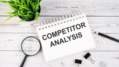 COMPETITOR ANALYSIS metin kavramı Tahta arka planda ofis araçları ile deftere yazmak