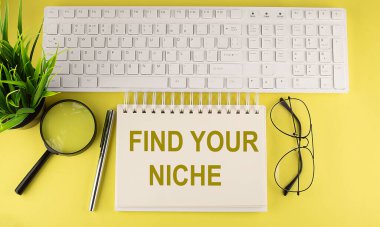 Ofis masası üst görünümü klavye ve defter metni ile Sarı zemin üzerinde NICHE 'nizi bulun