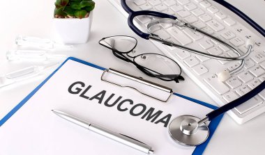 Beyaz arkaplandaki beyaz kağıda yazılmış GLAUCOMA metni. steteskop, gözlük ve klavye