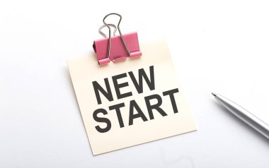 Beyaz arkaplanda kalem olan yapıştırma üzerine NEW Başlat metni