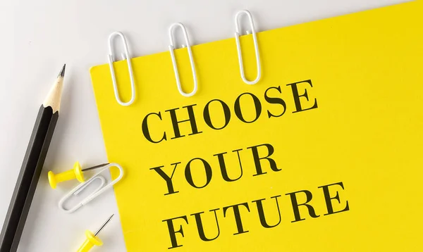 CHOOSE YOUR FUTURE word on the yellow paper with office tools on the white background