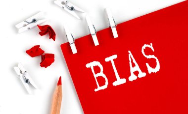 Beyaz arkaplanda ofis araçları olan kırmızı kağıt üzerindeki BIAS metni