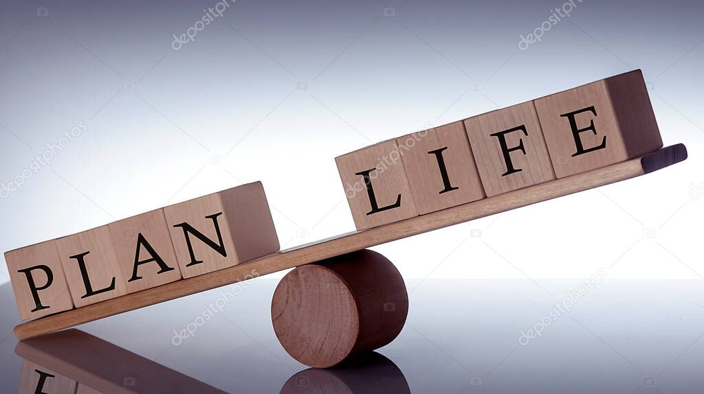 Wooden seesaw representing imbalance between PLAN and LIFE isolated on black background
