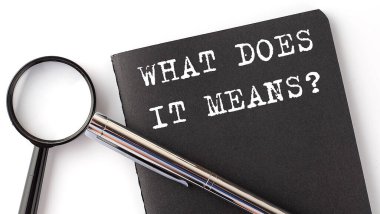 WHAT DOES IT MEANS - business concept, magnifier with white text message on black notebook