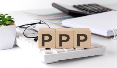 PPP written on wooden cube on keyboard with office tools