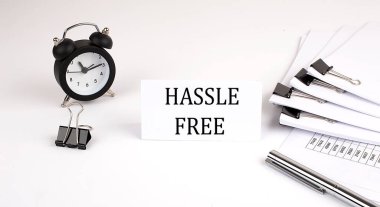 Ofis malzemeleri ve çalar saatin yanında beyaz bir arka planda HASSLE belgesi olan kart. İş dünyası