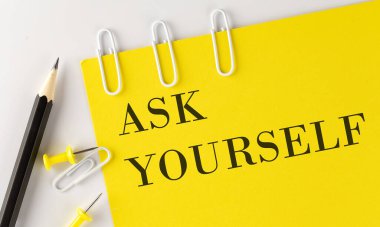 ASK YOURSELF word on yellow paper with office tools on the white background