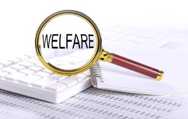 WELFARE word through magnifying glass on keyboard on chart
