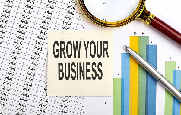 Business concept. Top view of stiscker with text GROW YOUR BUSINESS on the chart background