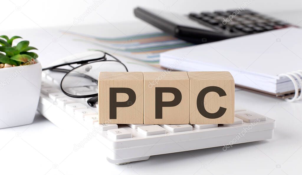 PPC written on wooden cube on keyboard with office tools