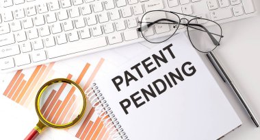 Not defterine klavye, grafik ve gözlük ile yazılmış PATENT PENDING metni