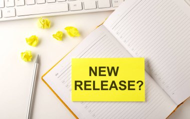 Günlükte klavye ve kalemle yapıştırılan YENİ RELEASE metin