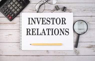 Hesap makinesi ve ofis araçları ile beyaz arkaplan üzerinde INVESTOR İlişkileri metin ile boş defter.