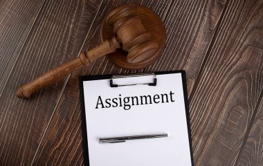 Kağıt üzerinde ahşap zemin üzerinde tokmak olan ASSIGNMENT metin