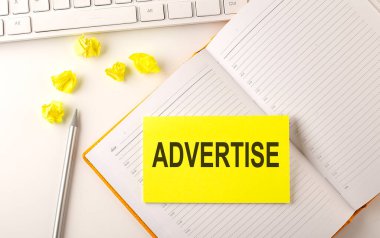 Günlük üzerindeki klavye ve kalem etiketli ADVERTISE metni