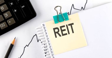 Kalemli çıkartmalar ve tahta arka planda REIT yazılı defter.