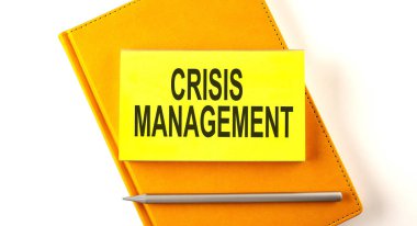 Sarı defter üzerindeki çıkartmada CRISIS MANAGEMENT yazsın
