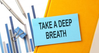 Sarı not defterine çizelge ve kalem yapıştırılmış bir derin nefes metni al.