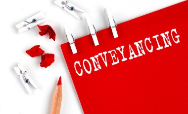 Beyaz arkaplanda ofis araçları ile kırmızı kağıt üzerinde CONVEYANCING metin