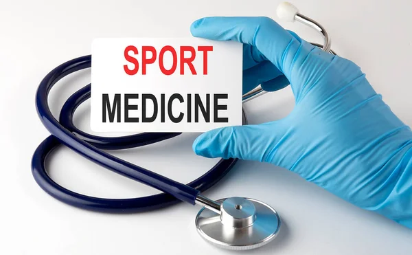 Card with text SPORT MEDICINE supplies, pills and stethoscope. Medical concept.