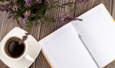 Ahşap zemin üzerinde boş bir beyaz defter, kalem ve bir fincan kahve aç