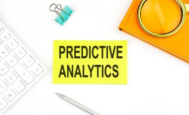 Beyaz arkaplan, hesap makinesi ve defterin yanında Predisitiv ANALYTICS metni olan etiket
