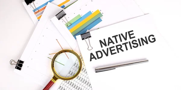 Native Advertising text on the white paper on the light background with charts paper